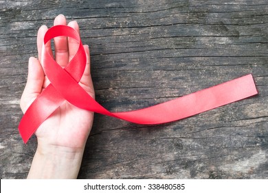 Aids Red Ribbon On Woman's Hand Support For World Aids Day And National HIV/AIDS And Aging Awareness Month Concept 