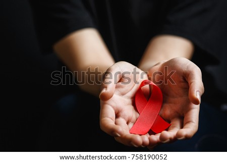 Aids ribbon on hands, hiv, red ribbon symbol of struggle,  on dark background