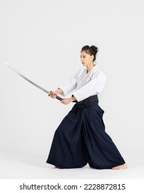 Mujer maestra del Aikido en el tradicional samurai hakama kimono con cinturón negro con espada, katana sobre fondo blanco. Estilo de vida saludable y concepto deportivo.