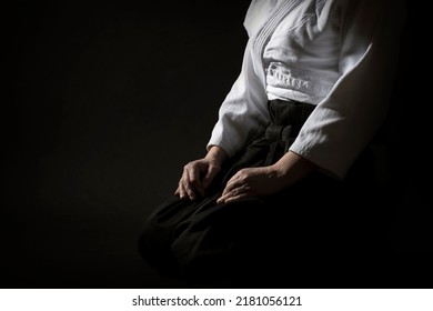 Aikido sentado posando con uniforme de hakama sobre fondo negro. Profundidad superficial del campo. SDF.