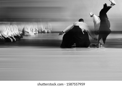 Aikido training. Black and white blurred background image. The teacher shows and explains the technique.