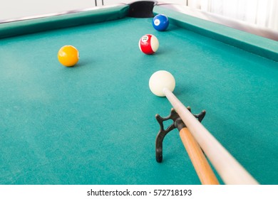 Aiming ball using extender stick during snooker billards game on green table
