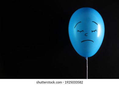 Air balloon with drawn sad face on black background. Space for text