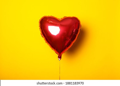 Air balloon in the form of a heart on a yellow background