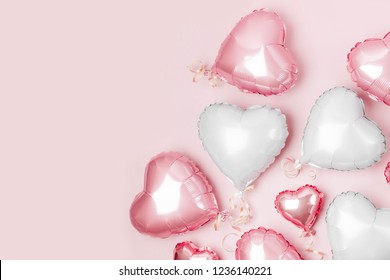 Air Balloons of heart shaped foil  on pastel pink background. Love concept. Holiday celebration. Valentine's Day or wedding/bachelorette party decoration. Metallic balloon