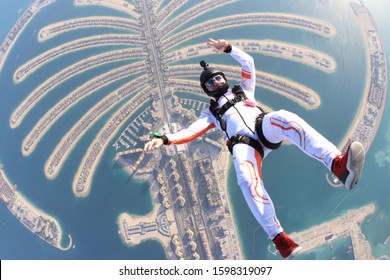Air beach jump. Freedom as a way of life. Parachutist performs an acrobatic trick in the Dubai air tourism. Parachutist in white suit. Skydiver is in air free fall. 

