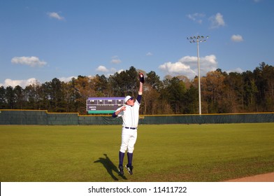 Air bound ball is snatched in the air by leaping baseball player.  Field and scoreboard in background. - Powered by Shutterstock