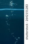 Air bubbles cluster beneath the surface, drifting slowly in the clear water. Light shimmers around them, creating a calm and refreshing underwater 