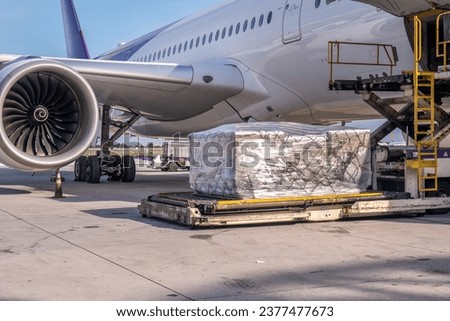 Air cargo logistic containers are loading to an airplane. Air transport shipment prepare for loading to modern freighter jet aircraft at the airport.