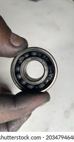 The Air Compressor Bearing Is Broken, Held By The Thumb And Forefinger That Is Smeared With Oil.