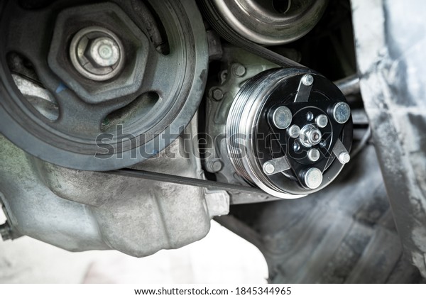 Air compressor clutch on car engine\
and belt and pulley transmission in repair process of\
car