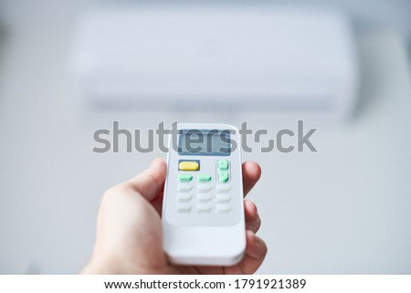 Air condition remote control. Hand with room conditioner remote control. Air temperature switch for cooling of space.