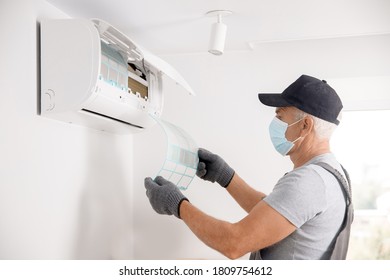 Air Conditioner Cleaning. Worker In Gloves And Medical Mask Checks Filter.