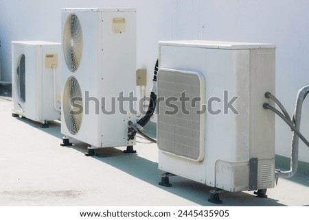 Air conditioner compressor installed on the wall of a building, along with industrial air conditioning units and ventilation systems. Cooling systems.	