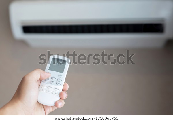 Air conditioner inside the room with close up man hand holding using