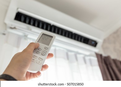 Air conditioner inside the room with woman operating remote controller. / Air conditioner with remote controller - Shutterstock ID 507015850