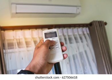 Air conditioner inside the room with woman operating remote controller. - Shutterstock ID 627506618