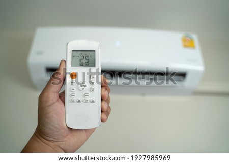 Air conditioner inside top the room man operating remote controller open air conditioner energy savings