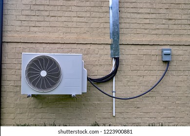 Air Conditioner Mini Split System Next To Home With Painted Brick Wall And Space For Text Copy