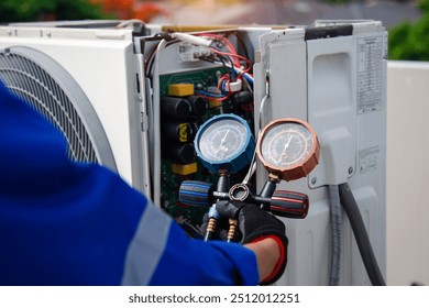 Air conditioner service .The air conditioner technician is using a gauge to measure the refrigerant pressure. air compressor. - Powered by Shutterstock