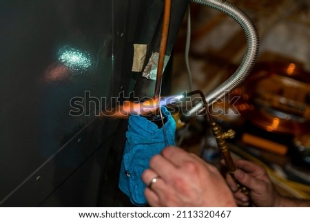 Air Conditioner Technician using a brazing torch to repair equipment