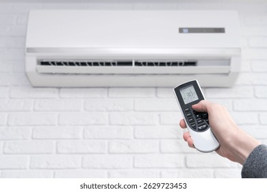 Ajuste de temperatura del aire acondicionado con control remoto en la habitación en casa. Mano Masculina Recortada Usando El Control Remoto Del Acondicionador De Aire En Casa.