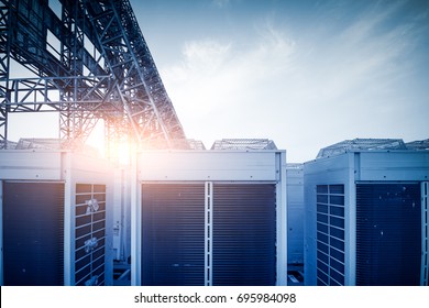 Air Conditioner Units (HVAC) On A Roof Of Industrial Building With Blue Sky And Clouds In The Background.