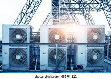 Air Conditioner Units (HVAC) On A Roof Of Industrial Building With Blue Sky And Clouds In The Background.