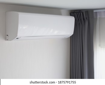 Air conditioner wall type, In living room near window with gray and white color curtain, Interior decoration minimal style in dwelling, Appliances that are installed and used a lot during the summer.