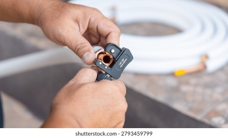 Air conditioning maintenance service using professional tube cutter tool, Close up of repairman hand cutting copper pipe for hvac system, Technician using pipe cutter for air conditioner installation
