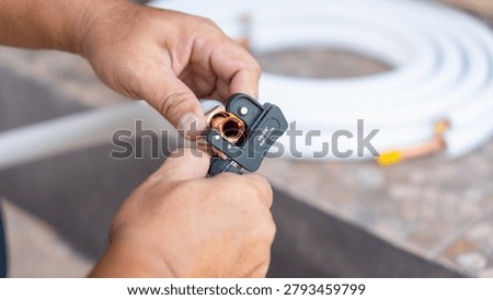 Air conditioning maintenance service using professional tube cutter tool, Close up of repairman hand cutting copper pipe for hvac system, Technician using pipe cutter for air conditioner installation