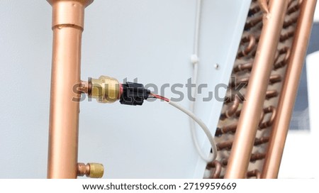 Air conditioning pipe sensor. Close-up of sensor on copper pipe of large air conditioner refrigerant pipe outdoors with selective focus.