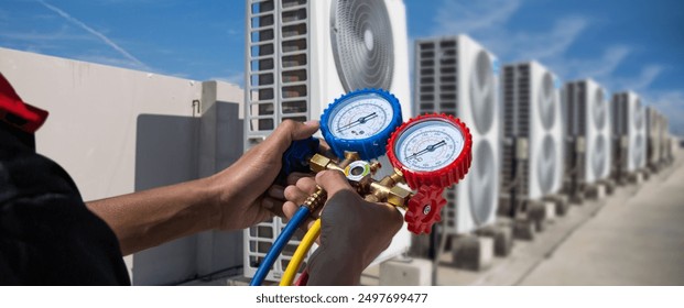 Air Conditioning service technician using measuring manifold gauge checking refrigerant and filling industrial air conditioner after duct cleaning HVAC condition system maintenance outdoor compressor. - Powered by Shutterstock