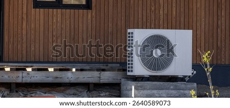 Air conditioning system in a modern frame house. Air conditioner compressor installed on the wall of a building, along with industrial air conditioning units and ventilation systems. Cooling systems.