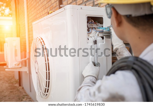 Air Conditioning Technician and A part of\
preparing to install new air conditioner. Technician vacuum pump\
evacuates and checking new air\
conditioner