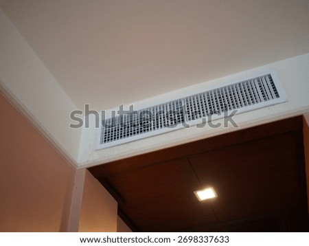 Air conditioning wall mounted ventilation system on ceiling in the white hotel room. Hotel room air ventilation grill on the wall.