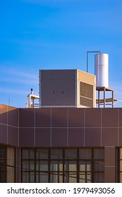 Air Cooled Water Chiller With Tank And Pipe System On Top Of Industrial Office Building Against Blue Sky In Vertical Frame