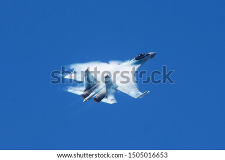 Air Force fighter jet performs a sharp maneuver in the sky, the pressure drop behind the wing causes visible vapor condensation