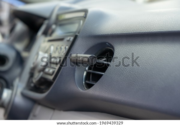 Air\
freshener in car vent,black interior, close up. Car air freshener\
mounted to ventilation panel, fresh flower\
scent