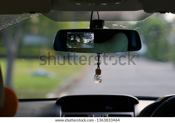 Air freshener hanging on rear view mirror of\
car at dashboard.