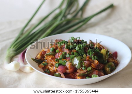 Air fried cottage cheese cubes and baby corn prepared with chilli sauce. It is an Indo Chinese dish, locally known as chilly paneer with baby corn. Short on white background.