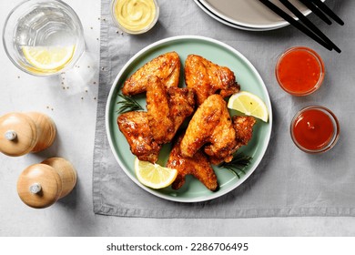 Air fryer chicken wings glazed with hot chilli sauce and served with different sauces.  gray background . top view