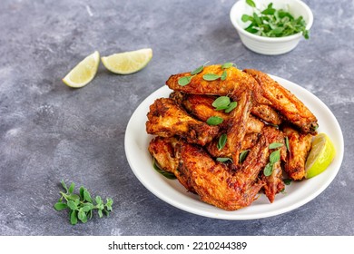 Air Fryer Chicken Wings On A Plate With Lemon Gaarnished With Marjoram