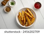 Air Fryer Roast Potatoes on white plate,potato wedges with tomatoes sauce.Top view.