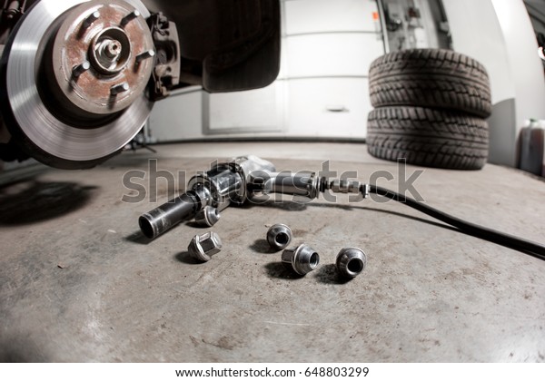 air gun to tighten a tire bolts on a suspended car\
at an auto shop