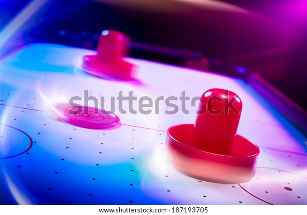 Air\
hockey table with dramatic lighting and motion\
trails