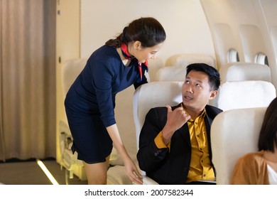 Air Hostess Or Flight Attendant Talking With Passengers On Airplane