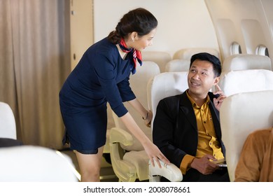 Air Hostess Or Flight Attendant Talking With Passengers On Airplane