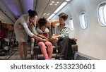 Air hostess helping kid to fasten  seat belt. Happy family with little girl sitting at airplane cabin. Airline transportation and travel concept.