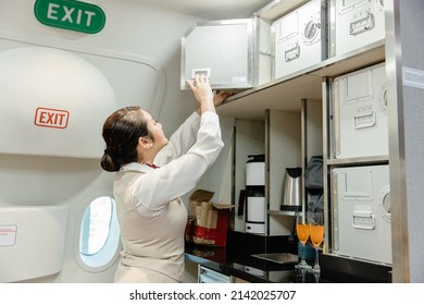 Air Hostess Prepare Food Using Safety Locker Crew Cabinet In Flight Cabin.